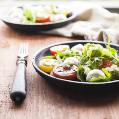 Fresh summer salad with mixed colour cherry tomatoes, lettuce, arugula and mozzarella cheese