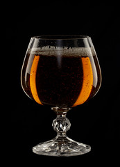 A glass of cognac on a black background close-up