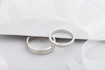 Two silver wedding rings with diamonds on gray background