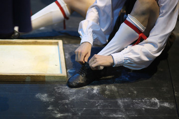 The ballet dancer, sitting on the floor, puts on special ballet shoes before the performance