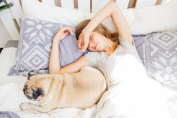 Young woman with her dog in a bed. Breakfast in bed