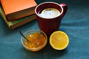 Black Tea with Lemon, Half a Lemon, Books and Lemon Jam  on a Textile  Background. Autumn Concept