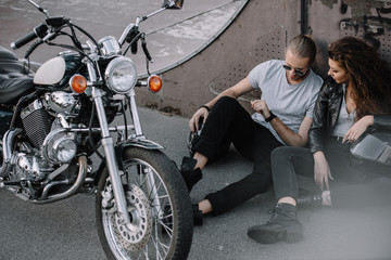 Fototapeta na wymiar girlfriend and boyfriend sitting on asphalt with classical chopper motorcycle