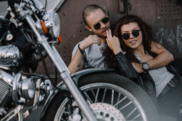 Plakat couple hugging and smoking cigarette on asphalt with chopper motorbike
