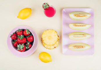 Fresh strawberries in bowl and melone on pastel yellow background.