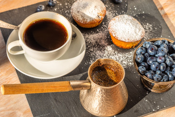Delicious breakfast - a cup of coffee and muffins with blueberries on a slate platter