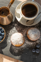 Delicious breakfast - a cup of coffee and muffins with blueberries on a slate platter