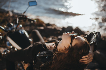 Obraz na płótnie Canvas beautiful girl in sunglasses lying on classical motorcycle