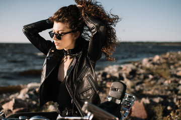 Fototapeta na wymiar beautiful curly girl in sunglasses sitting on motorcycle