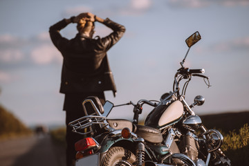 back view of confused biker with broken motorcycle on road, selective focus