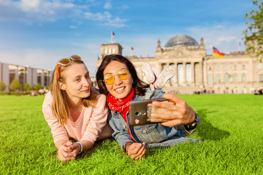 Two happy woman making selfie on background of Reichstag Bundestag building in Berlin. Travel and love concept in Europe