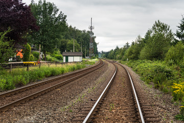 Railway Tracks Lined with Trees on a Cloudy Summer Day. Fort Langley, BC, Canada.