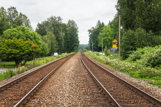 Railroad Tracks in the Countryside of British Columbia under Cloudy Sky in Summer