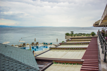Obraz premium back yard patio cafe exterior with view from top of building to open sea waterfront district in gray rainy day time before storm