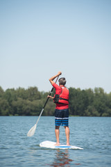 man enjoying a ride on the lake with paddleboard