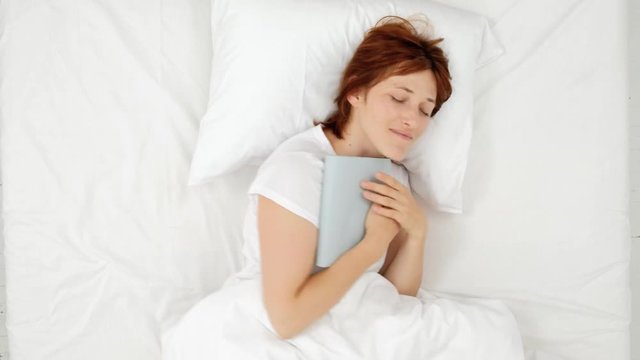 Woman in bed with book on her hand and sleep. top view