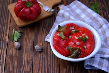 Appetizer, roasted pickled sweet red pepper in a white bowl on a wooden background. Serbian cuisine.