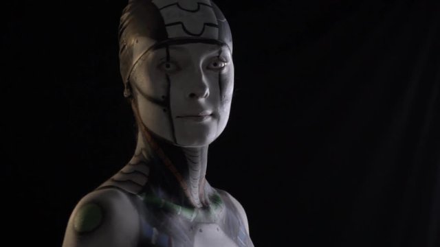 A cyborg woman on a black background turns to the camera, humanoid woman
