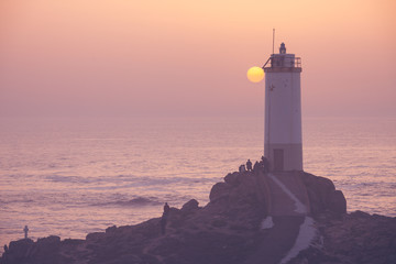 People watching ocean sunset. Roncudo Lighthouse at Spain