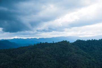 Landscape image of greenery rainforest hills in foggy day with cloudy sky background