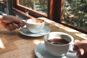 Closeup image of two people holding and drinking coffee in the morning
