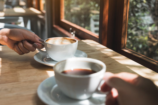Closeup image of two people holding and drinking coffee in the morning