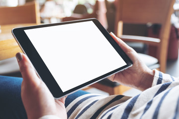 Mockup image of woman's hands holding black tablet pc with blank white desktop screen while sitting in cafe