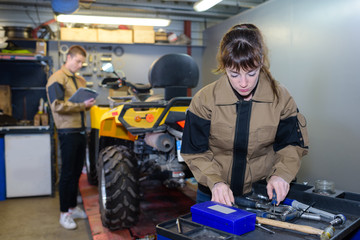 Fototapeta premium woman worker is repairing tractors engine with the wrench