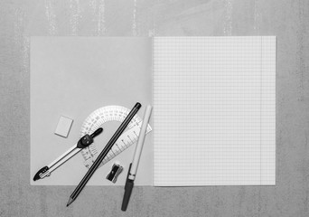open school notebook mock up with copy space, ballpoint pen, pencil, eraser, compasses, steel protractor and pencil sharpener top view, black and white photo - Powered by Adobe