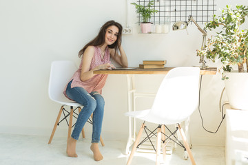 people, interior and technology concept - young woman sitting at a table with tablet at room