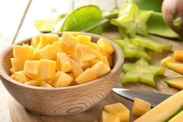 Bowl with cut fresh mango on wooden table, closeup