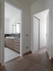 interior shot of a apartment in the foreground the hardwood floor in the background view of a modern bathroom