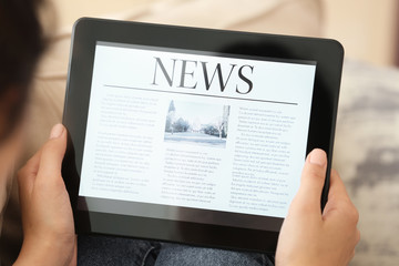 Woman reading news on tablet computer indoors
