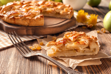 Piece of tasty apple pie on wooden table