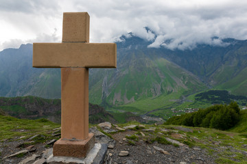 Cross on a pyramid of stones on Kazbek Mount Background near Gergeti Trinity Church in Georgia..
