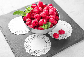 Bowl with delicious raspberries on slate plate