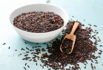 Bowl and scoop with raw wild rice on table