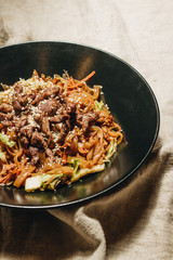 Meat with noodles in black plate, Asian cuisine, chopsticks