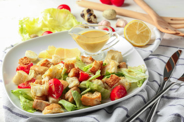 Plate with tasty Caesar salad on table, closeup