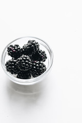 Fresh organic blackberries in small bowl on white background