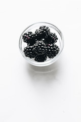 Fresh organic blackberries in small bowl on white background