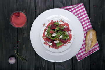 salat mit erdbeeren von oben auf dunklem holz untergrund mit rot karriertem handtuch und dressing