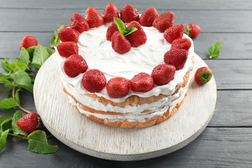 Delicious cake with strawberries on wooden table