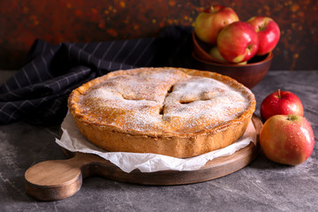 Board with delicious apple pie on dark table