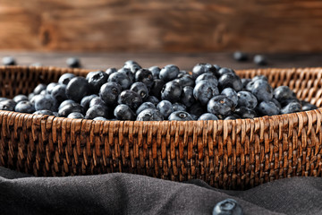 Wicker basket with ripe blueberries on table