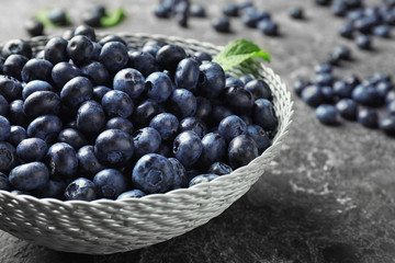 Bowl with ripe blueberries on grunge table, closeup