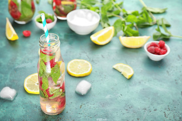 Glass bottle of fresh raspberry mojito on green table