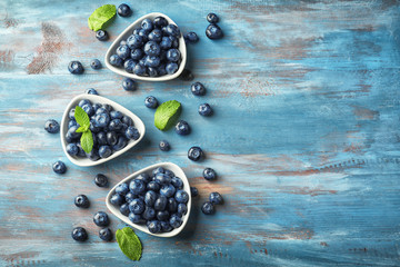 Bowls with ripe blueberries on wooden table