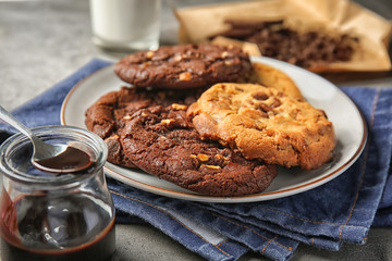 Plate with tasty cookies and melted chocolate on table
