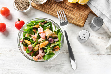 Bowl of delicious vegetable salad with seafood on table